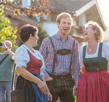 Drei Personen in Tracht gekleidet lachen zusammen